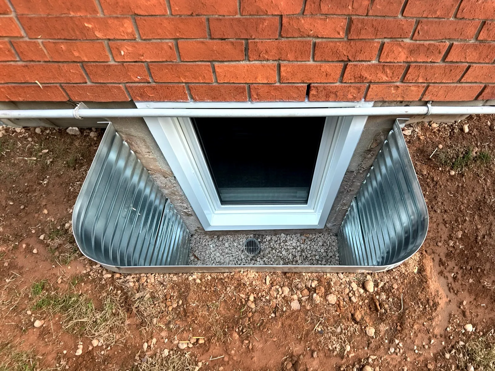 Basement opening enlarged to a code sized egress window with a galvanized well