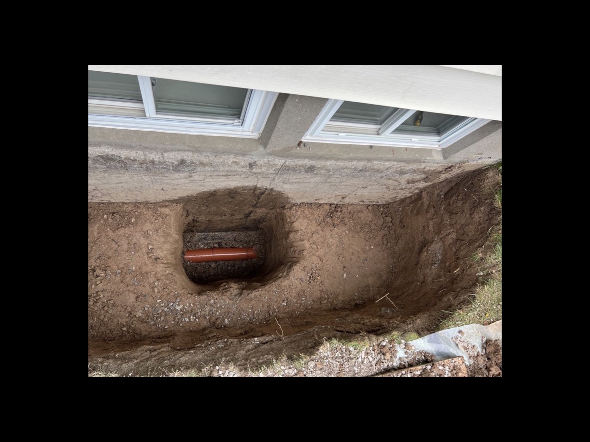 Hand dug window well excavation with the drain pipe reached below the basement windows