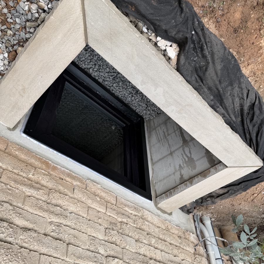 Masonry window well with rock face limestone sill and black egress window